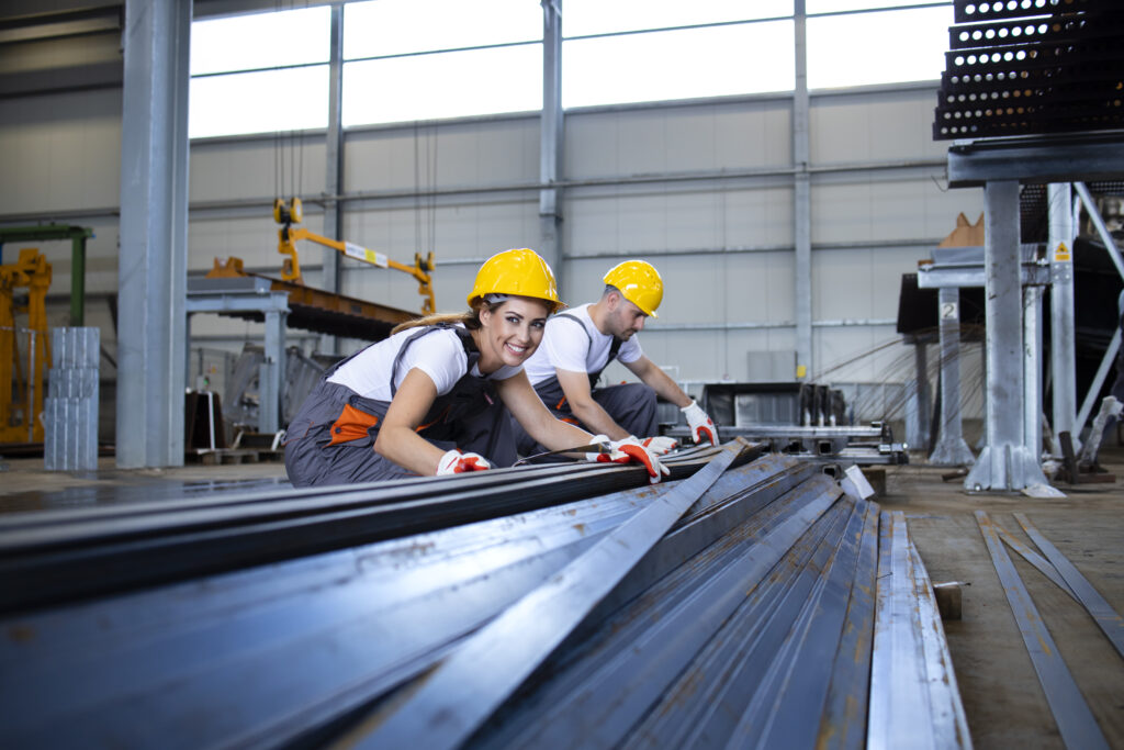 Industrial workers working in factory hall with metal.